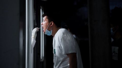 بیجنگ، چین میں 22 جون 2022 کو ایک طبی کارکن کوویڈ 19 کے لیے ایک شہری سے جھاڑو کا نمونہ لے رہا ہے۔