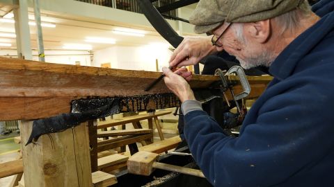 Volunteer Simon Lamb chisels the bow underlout for the new Sutton Hoo ship.