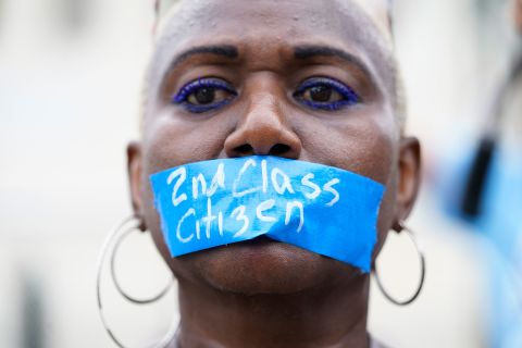A pro-abortion rights activist wears tape across their mouth reading 