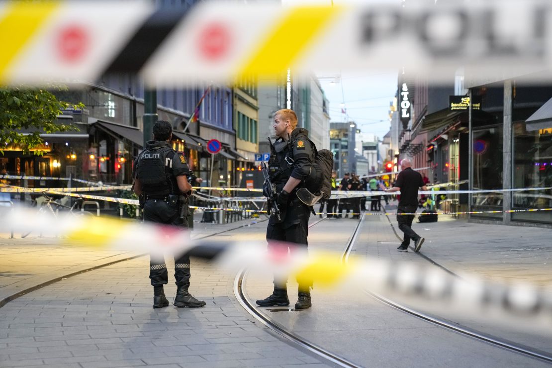 Police stand guard at the site of a mass shooting in Oslo, early Saturday.