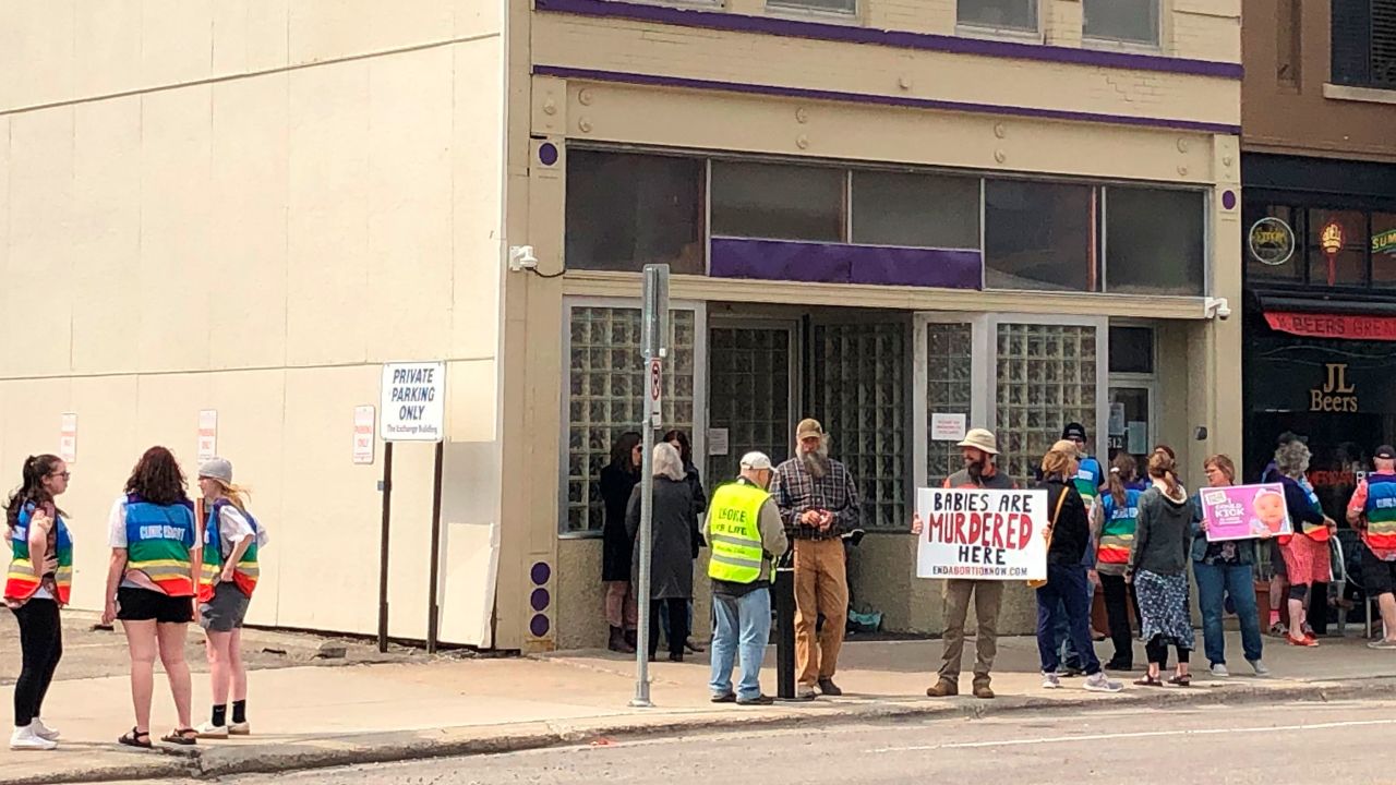 A photo from May shows both protesters and patient escorts in rainbow-colored vests outside of Red River Women's Clinic.