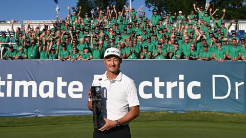 Li poses with the winner's trophy on the 18th green alongside event volunteers.