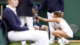 Jodie Burrage helps a ball boy after they fainted during her Ladies' singles first round match against Lesia Tsurenko during day one of the 2022 Wimbledon Championships at the All England Lawn Tennis and Croquet Club, Wimbledon. Picture date: Monday June 27, 2022. 