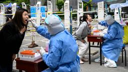 Health workers take swab samples from people to be tested for Covid-19 coronavirus at a makeshift testing site along a street in Beijing on May 11, 2022. (Photo by Jade GAO / AFP) (Photo by JADE GAO/AFP via Getty Images)