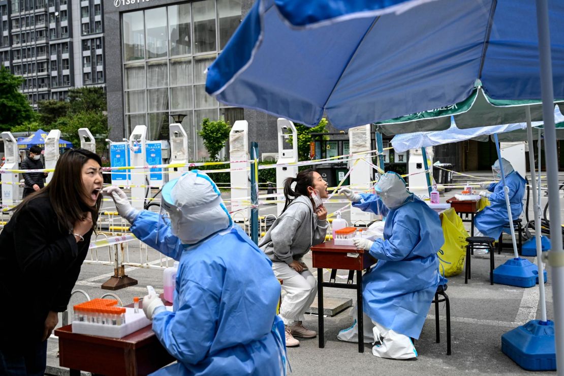 Health workers take swab samples to be tested for Covid-19 at a makeshift testing site along a street in Beijing on May 11, 2022.