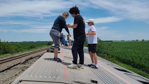 La gente se para al costado de un tren de Amtrak que descarriló el lunes en Menton, Missouri.