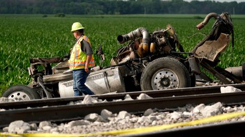 A worker looks over a dump truck that collided with an Amtrak train, causing it to derail.