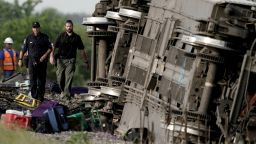 Law enforcement personnel inspect the scene of an Amtrak train which derailed after striking a dump truck Monday, June 27, 2022, near Mendon, Mo. (AP Photo/Charlie Riedel)