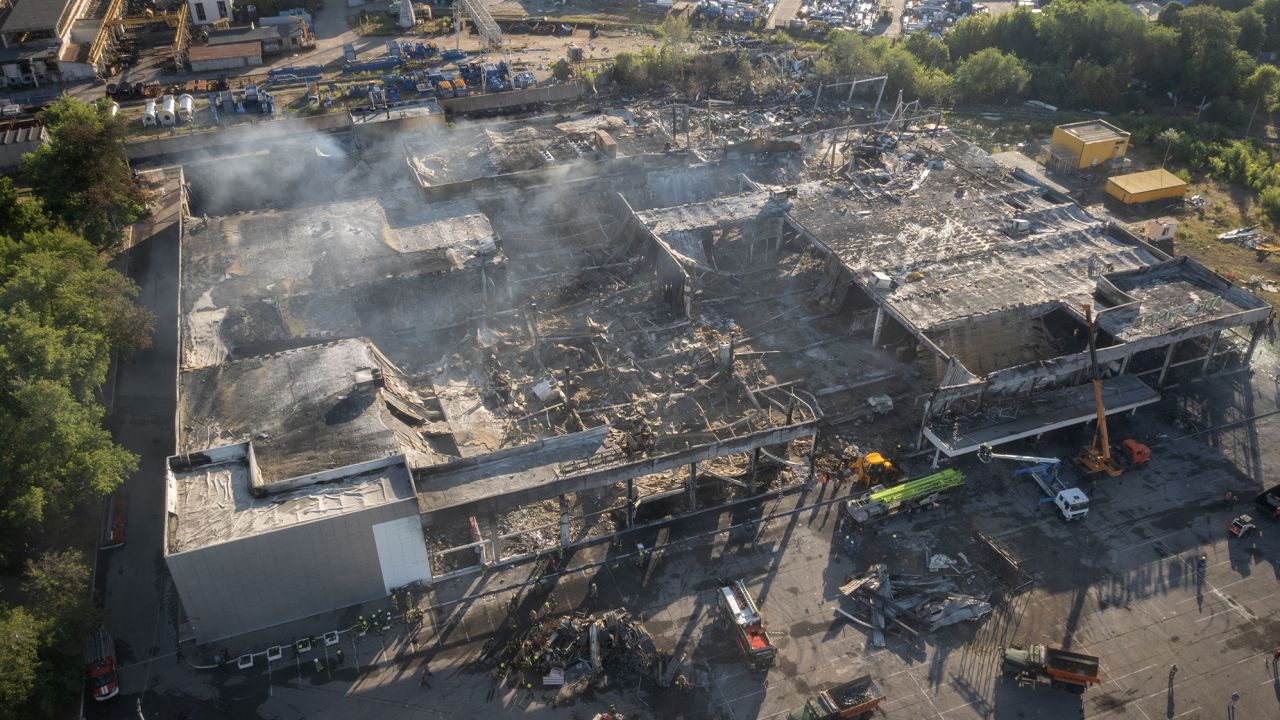 Firefighters work to remove debris at a shopping center burned after a rocket attack in Kremenchuk, Ukraine.