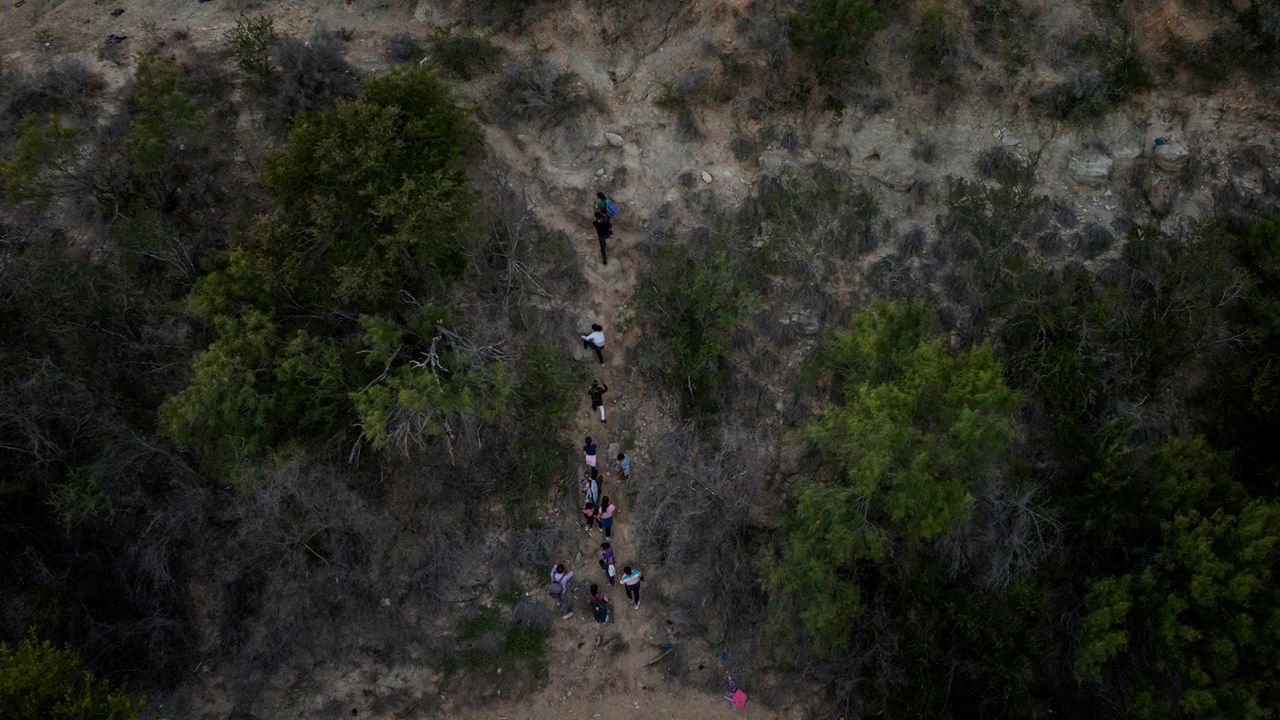 Migrant families climb a steep bank after crossing the Rio Grande into the US on June 16.