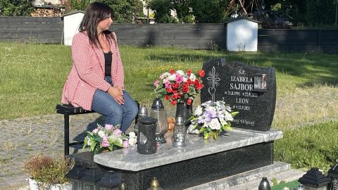 Barbara Skrobol, Izabela's sister-in-law, sits beside her grave in southern Poland.