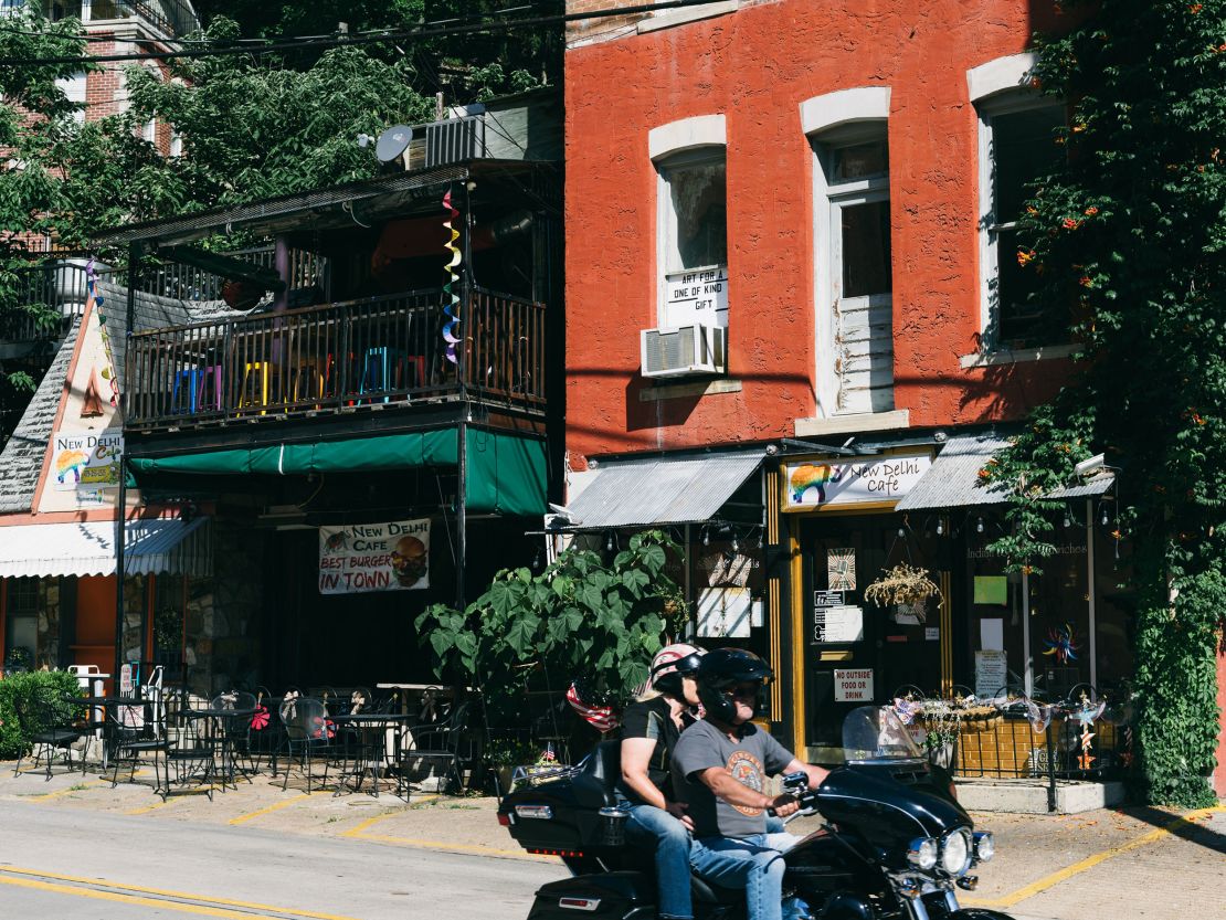 Riders on a motorcycle drive by a restaurant in downtown Eureka Springs on June 21.