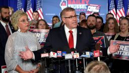 Republican gubernatorial primary candidate Darren Bailey, center, stands with his wife, Cindy Stortzum, and responds to reporters' questions after winning the Republican gubernatorial primary, Tuesday, June 28, 2022, in Effingham, Ill. Bailey will now face Democratic Gov. J.B. Pritzker in the fall. 