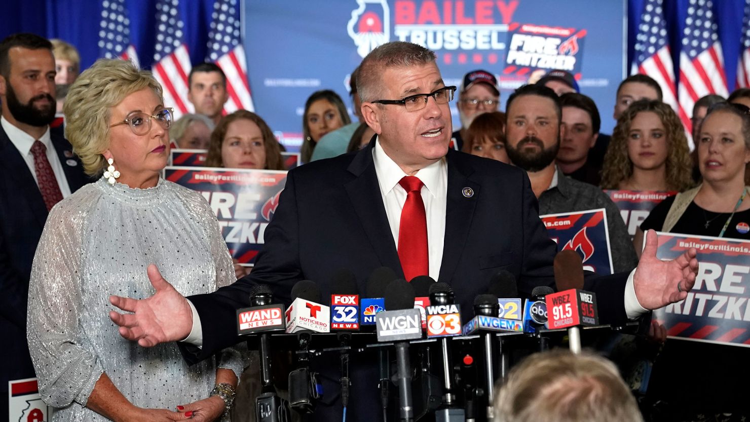 Republican gubernatorial primary candidate Darren Bailey, center, stands with his wife, Cindy Stortzum, and responds to reporters' questions after winning the Republican gubernatorial primary, Tuesday, June 28, 2022, in Effingham, Ill. Bailey will now face Democratic Gov. J.B. Pritzker in the fall. 