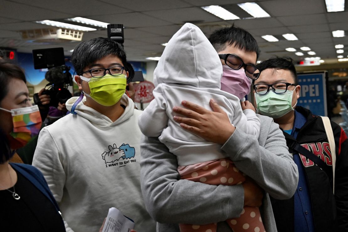 Chen Jun-ru (right, holding his daughter), and Wang Chen-wei (left) arrive at the Xinyi District Office in Taipei on January 13, 2022.