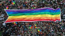 TOPSHOT - Aerial view showing people displaying a large banner in the colours of the Rainbow flag during the Pride Parade in Mexico City on June 25, 2022. (Photo by Alfredo ESTRELLA / AFP) (Photo by ALFREDO ESTRELLA/AFP via Getty Images)