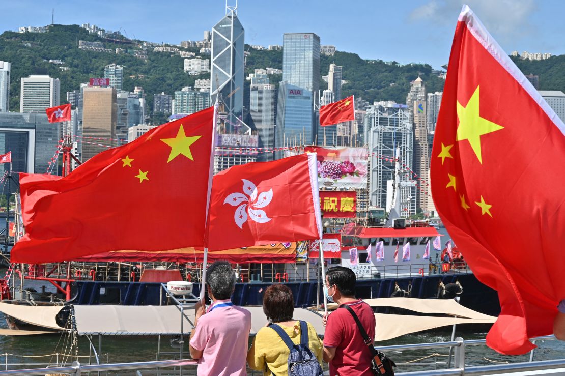 People wave Chinese and Hong Kong flags as fishing boats carrying banners celebrating the 25th anniversary of Hong Kong's handover to China sail through the Victoria Harbour.