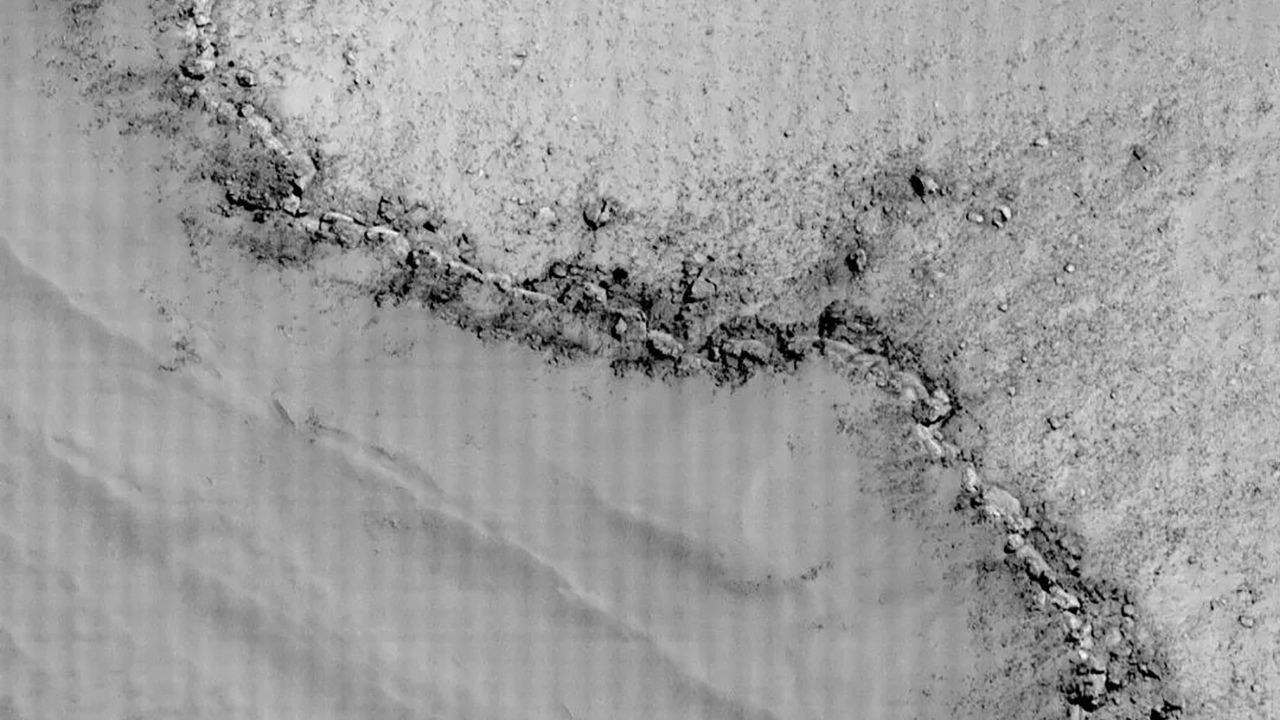 A high-resolution image showing the edge of a crater on Mars, and the beginning of the pit.