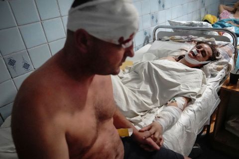 A wounded couple holds hands at a hospital in Kremenchuk, Ukraine, on Monday, June 27. They were hurt when a <a href=