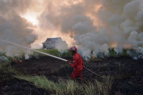 A firefighter works to extinguish a peatland fire in Indonesia's Ogan Ilir Regency on Tuesday, June 28.