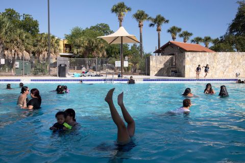 Ciaralyn Dysart does a handstand in a San Antonio public pool that had just opened for the season on Friday, June 24. Millions of Americans were under heat advisories and looking for ways <a href=