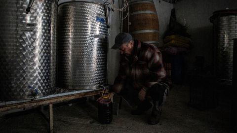 Dimitris Matisaris' father, a retired PPC worker, fills a bottle of wine at his son's winery.