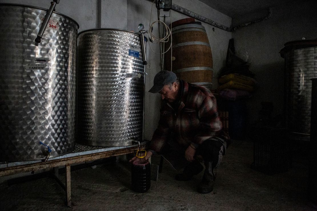 Dimitris Matisaris' father, a retired PPC worker, fills a bottle of wine at his son's winery.