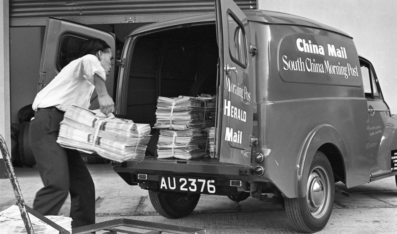 A man loads a stack of newspapers into a van for delivery outside the South China Morning Post building in the neighborhood of Quarry Bay.