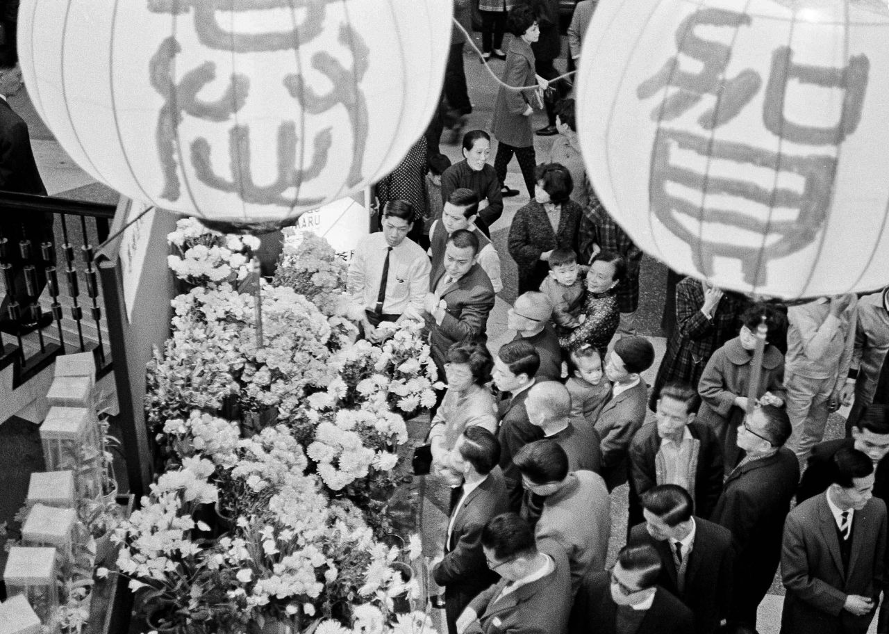 Huge paper lanterns decorated for the Lunar New Year hang above a flower vendor as thousands of people pour into the streets of Hong Kong in 1964. 