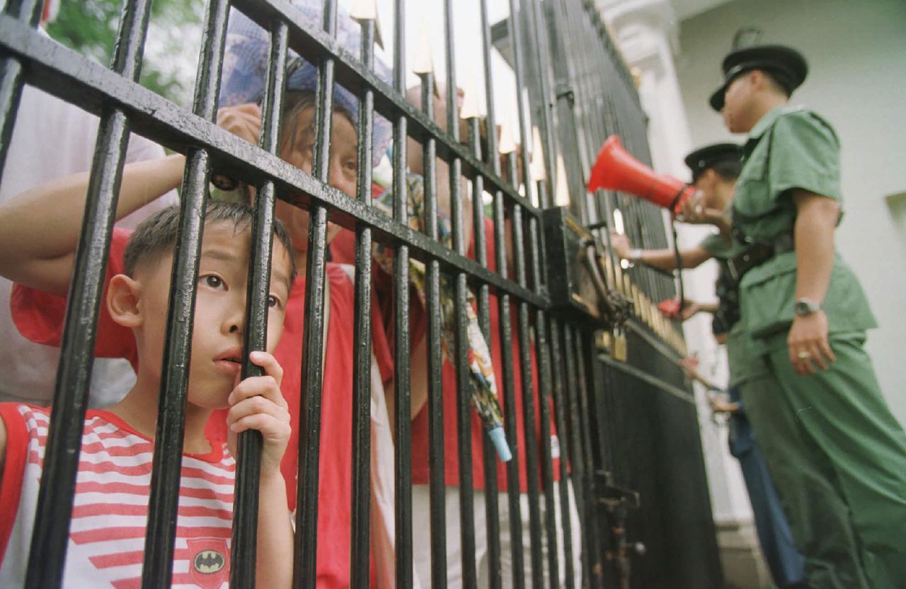 Hong Kong police close the gates of the Government House as a child looks inside through the fence following Patten's departure from his official residence on June 30, 1997.