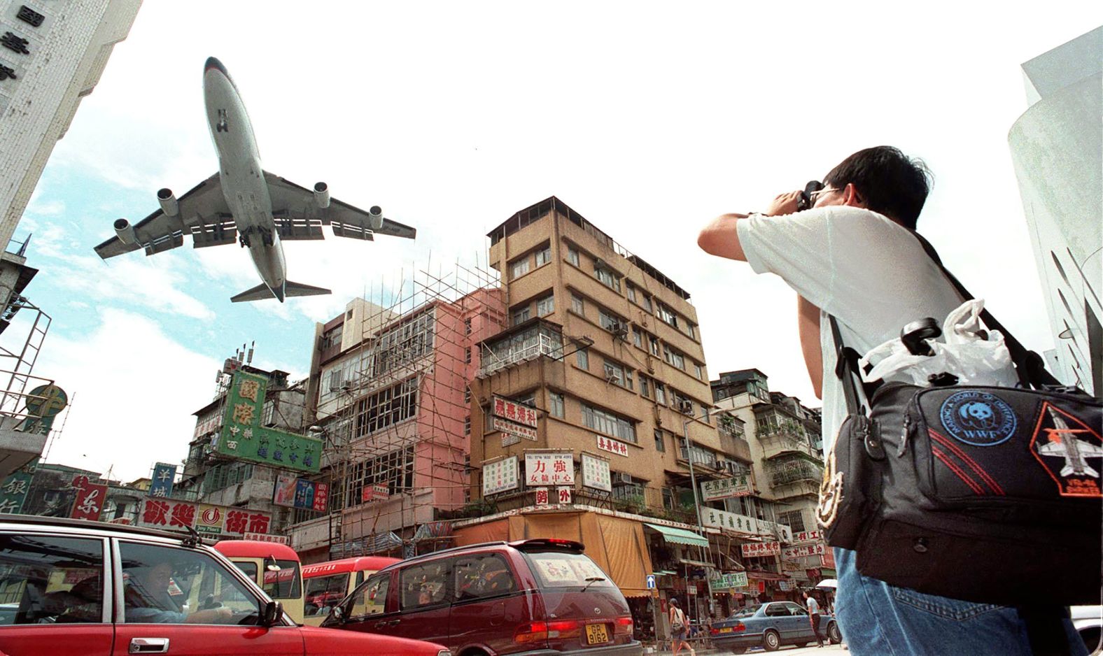 A man takes photographs as a jetliner makes its approach for landing at Hong Kong's Kai Tak airport in 1998. Many people gathered in and around Kai Tak airport to watch landings and take-offs the day before its closure.