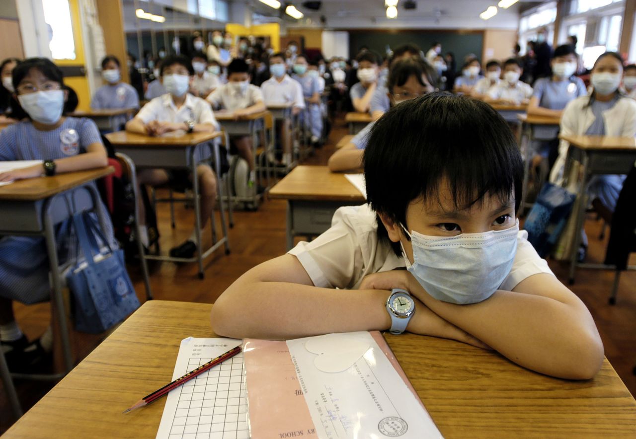 Primary school students, wearing surgical masks in addition to their regular uniforms, attend an anti-SARS lesson in Hong Kong in 2003.