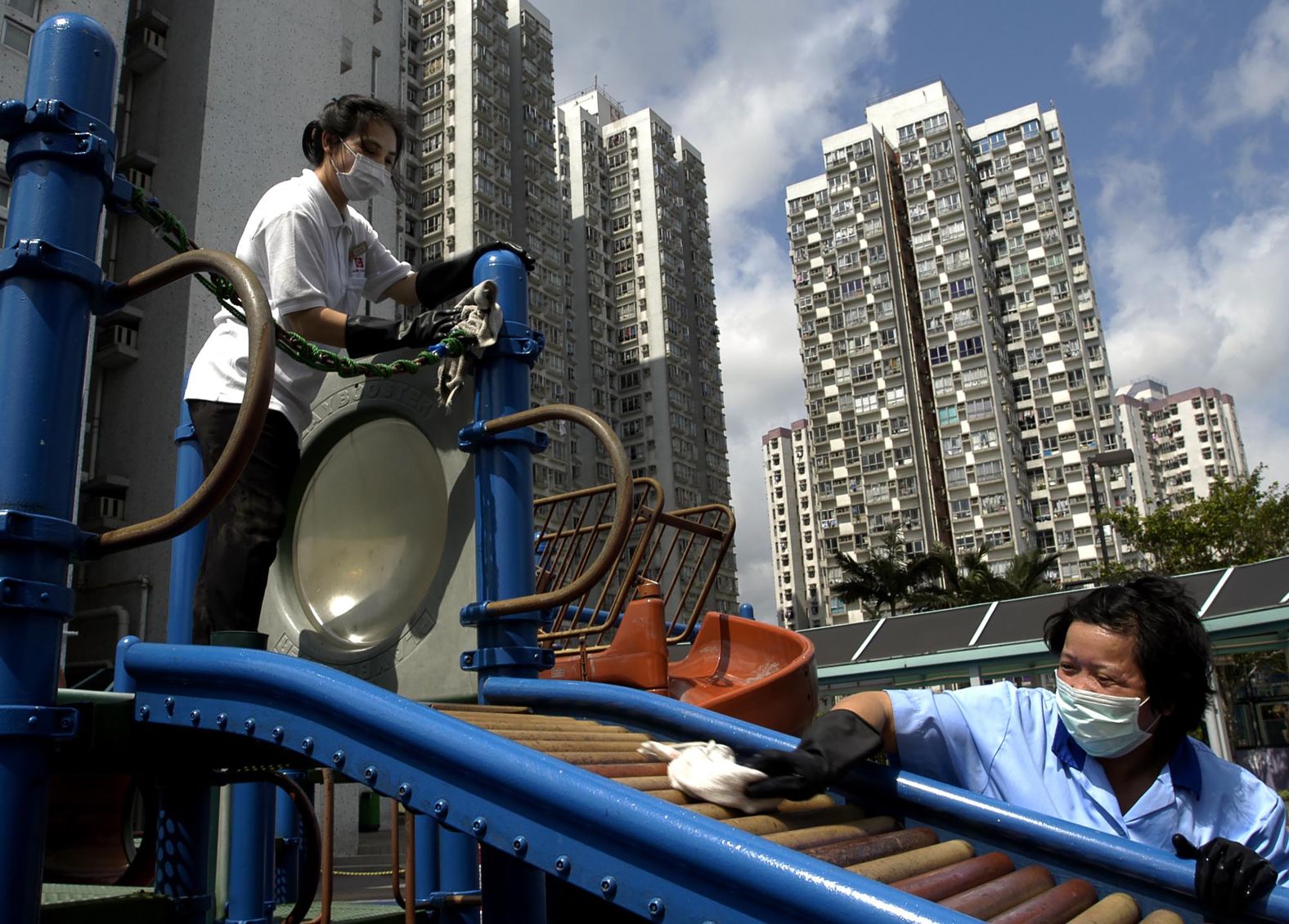 Workers wearing masks clean a playground in Hong Kong in 2003.