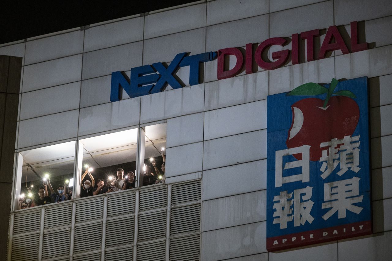 Employees at the headquarters of the Apple Daily newspaper shine cell phone flashlights to the crowd of supporters below on June 23, 2021, the last night of its operations. The outspoken pro-democracy newspaper printed its final issue on June 24 after authorities froze the company's assets and arrested top editors and executives.