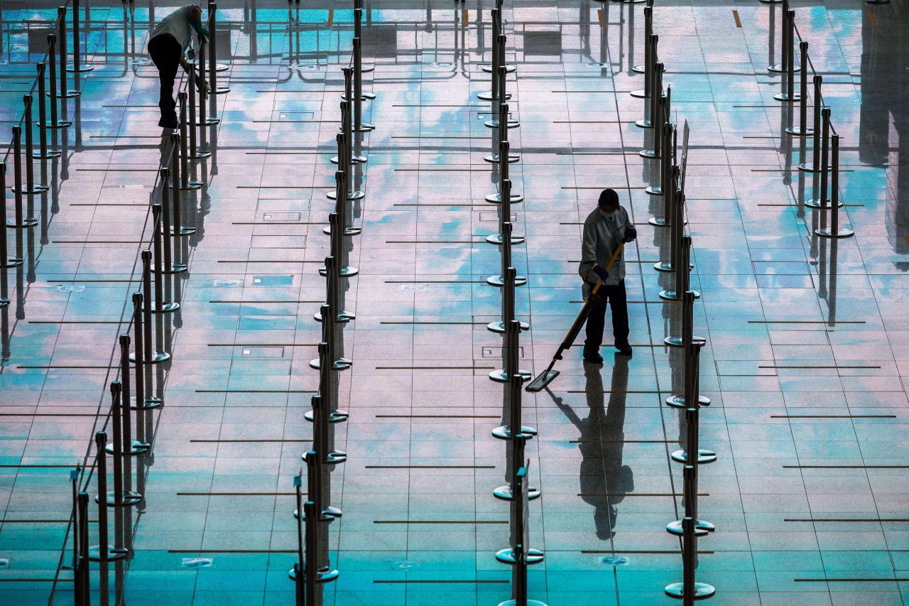Workers at Hong Kong International Airport clean an area for arriving passengers before they boarded buses to quarantine hotels in March 2022.