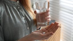 Young woman with abortion pill and glass of water