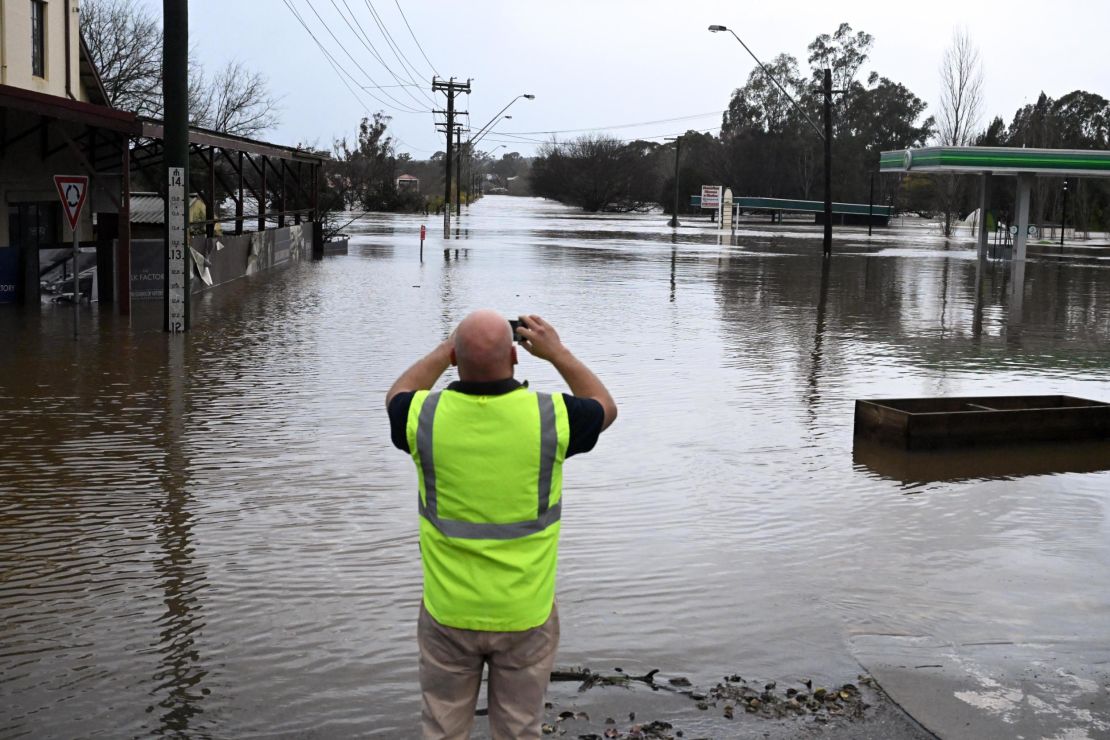 A local takes a photo of a road inundated by floodwaters in Camden in South Western Sydney, Sunday, July 3, 2022.