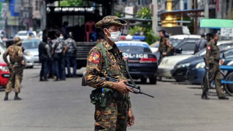 A soldier stands guard along a road as security forces search for protesters in Yangon.