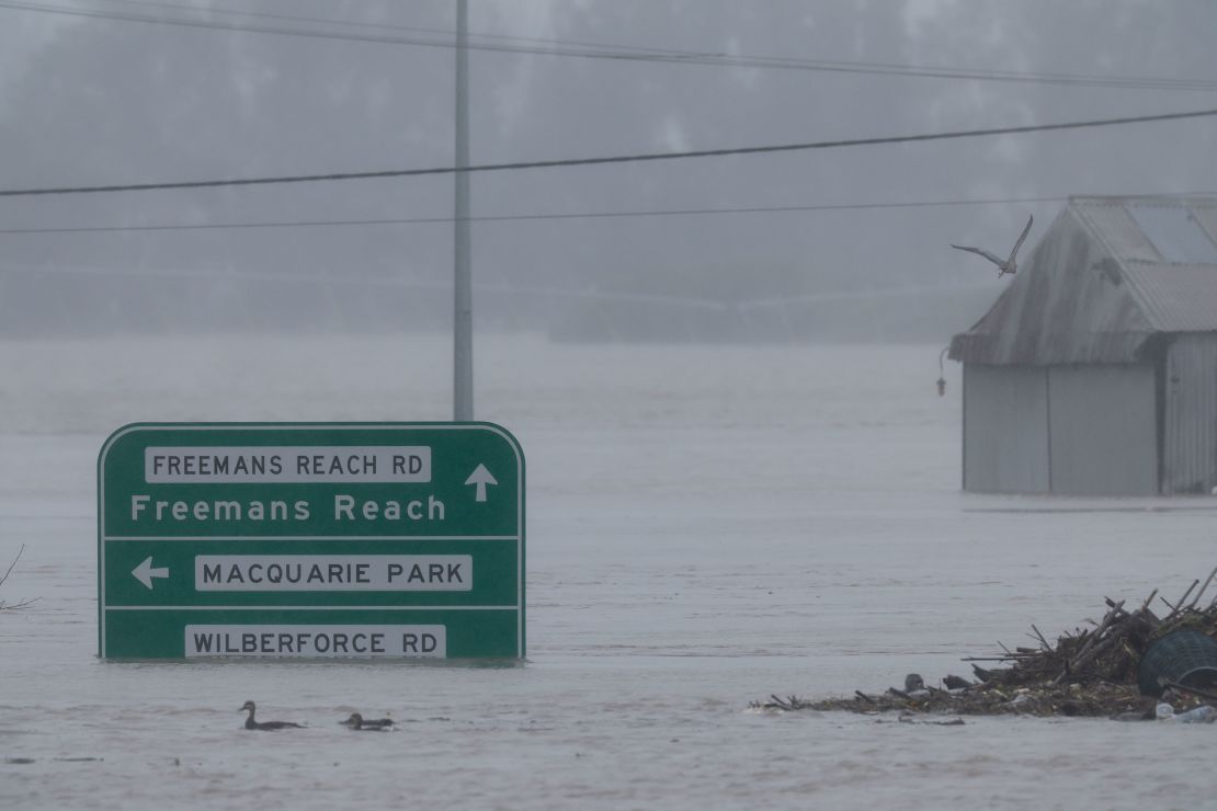 Road signs are seen submerged under floodwater along the Hawkesbury River in the suburb of Windsor, on July 4, 2022.