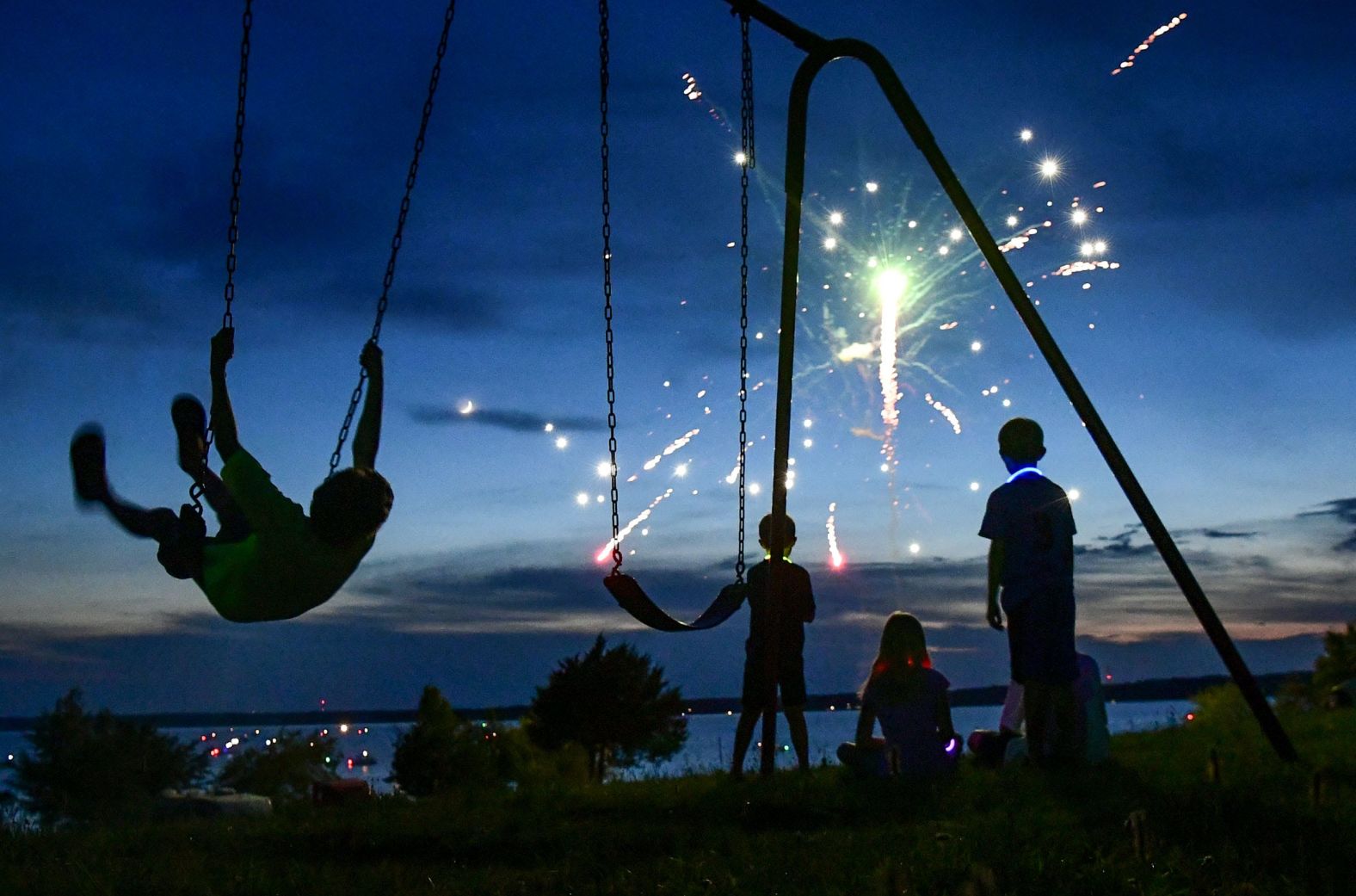 Wyatt Savori swings and watches fireworks in Anderson, South Carolina, on Thursday.