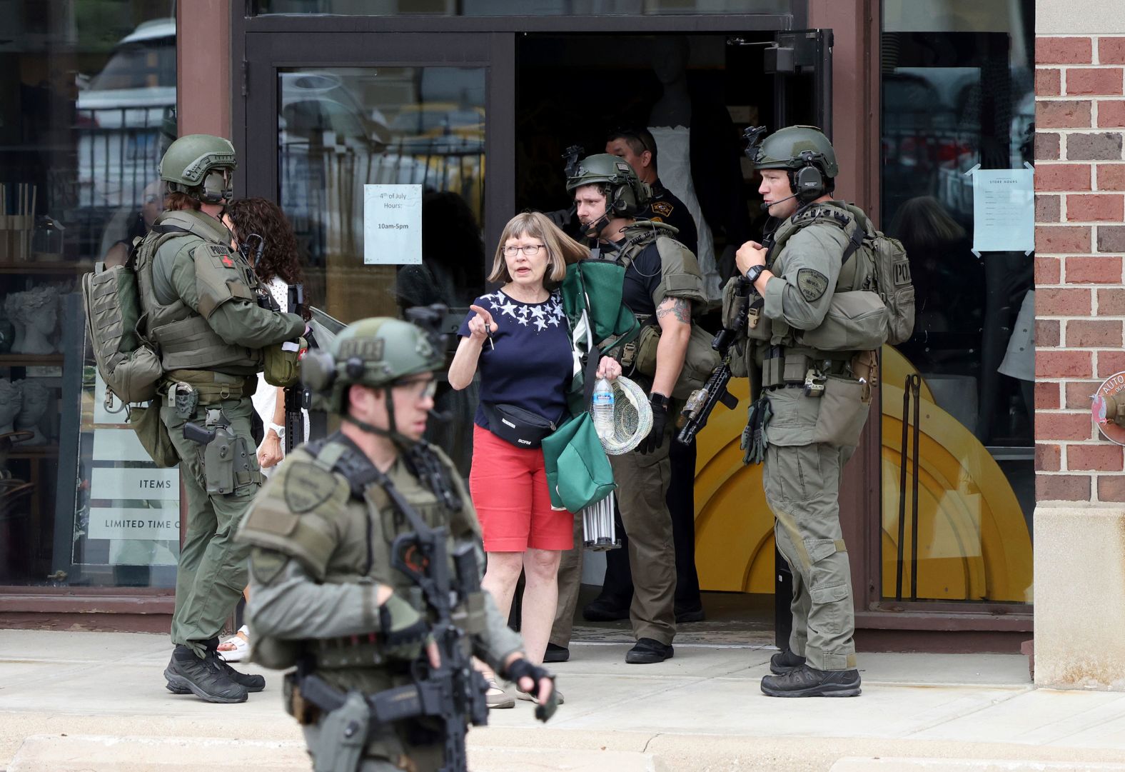 Law enforcement officers help evacuate people from a store in Highland Park on Monday. 