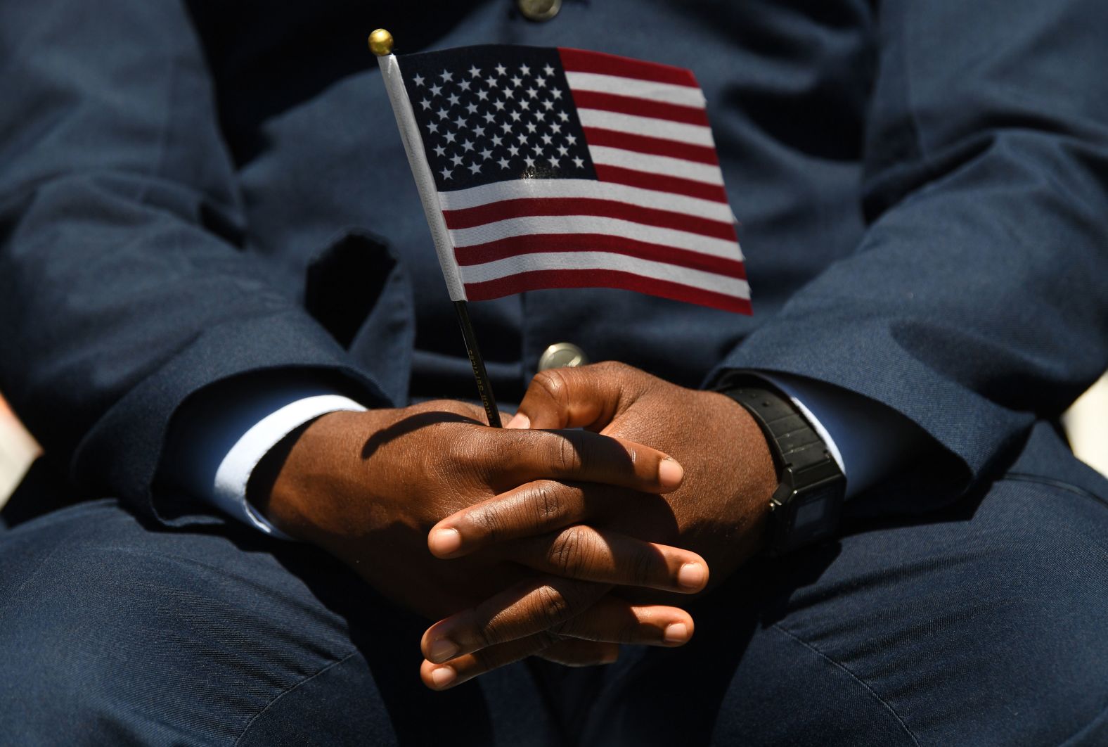 A military member holds a flag while taking part in a naturalization ceremony as people gather to celebrate the Fourth of July in Mount Vernon, Virginia, Monday.
