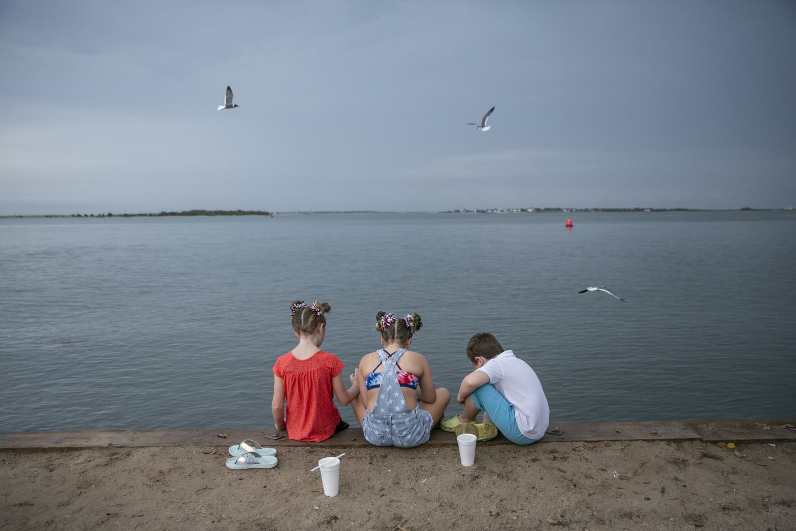 Children eat on a seawall after the annual Independence Day Parade in Southport, North Carolina, Monday.