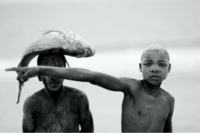In 2018, Macilau published his "Faith Series," where he explored how Mozambicans preserve their traditional religious rituals. He says it's important to capture these moments to "analyze or to see how the religion changed with the passage of time." Macilau notes he shot "Two Boys with a Fish" (pictured) to help paint a picture of the scene that was unfolding on the beach. "I'm not focusing specifically about the religion," he says, "I'm focusing about what can happen in the same space." In this instance, he says the kids could have been on the beach to "catch a fish, to sell fish, to play, or ... going there to pray."