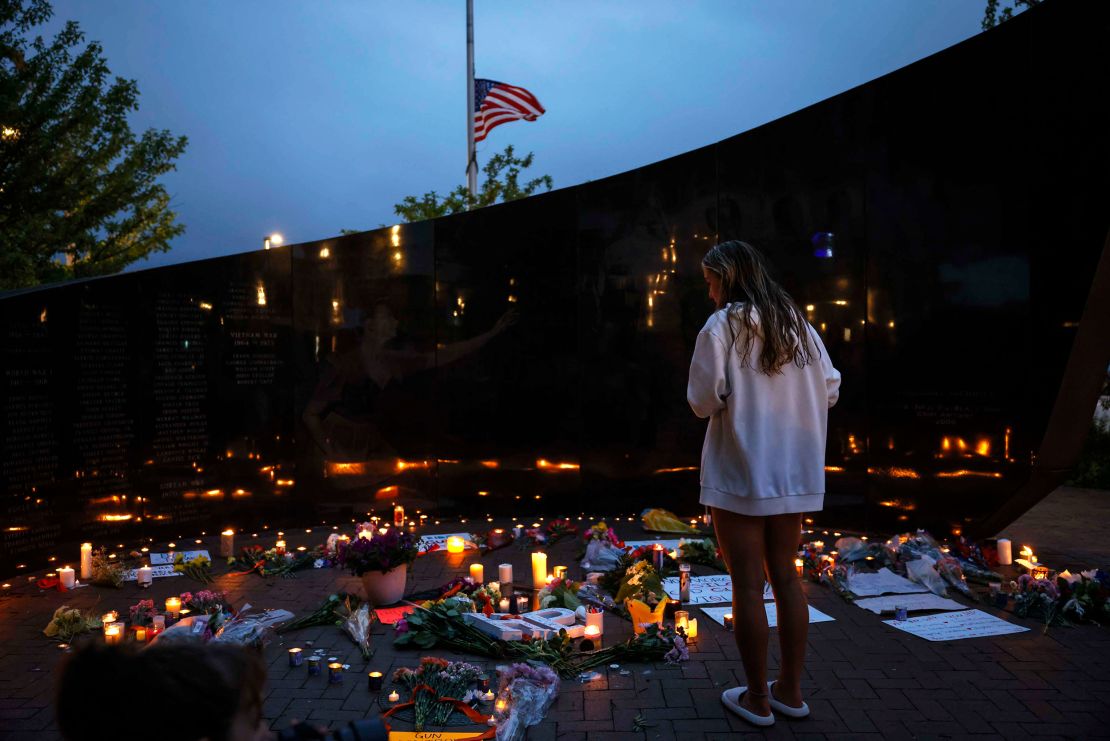  A woman views the candles and flowers left the victims of the parade shooting on July 5, 2022 in Highland Park.