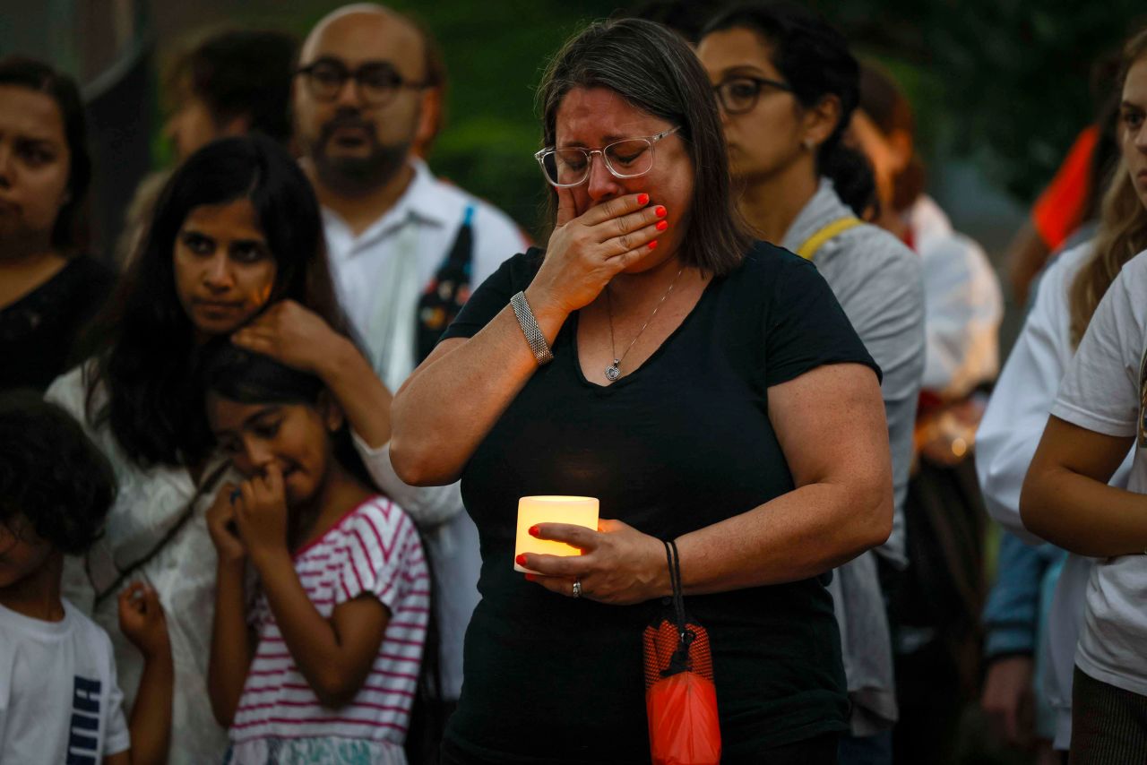 Elizabeth Zweiback cries during a candlelight vigil for the victims. Zweiback and her husband were marching in the parade with the Maureen Township food bank when the attack started. "We ran for our lives," she said. 