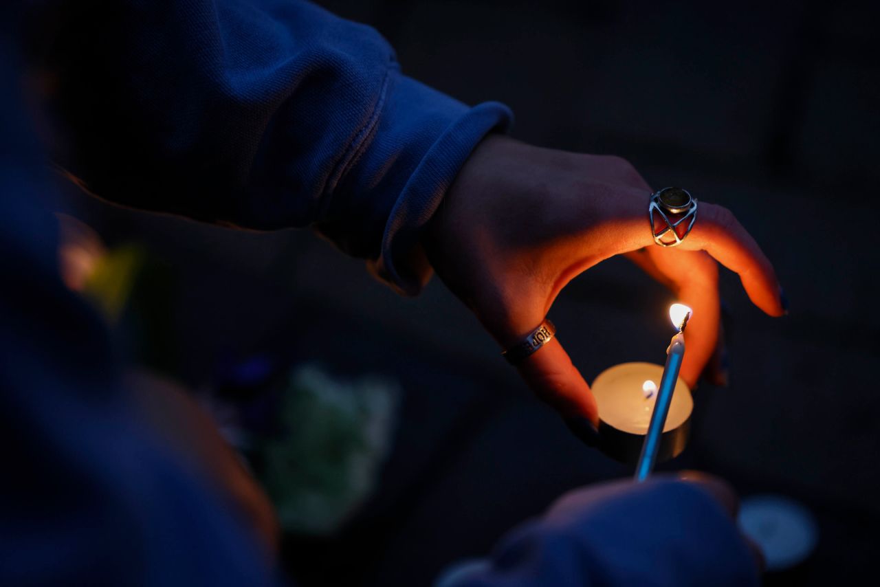 A woman lights a candle at a memorial for the victims.