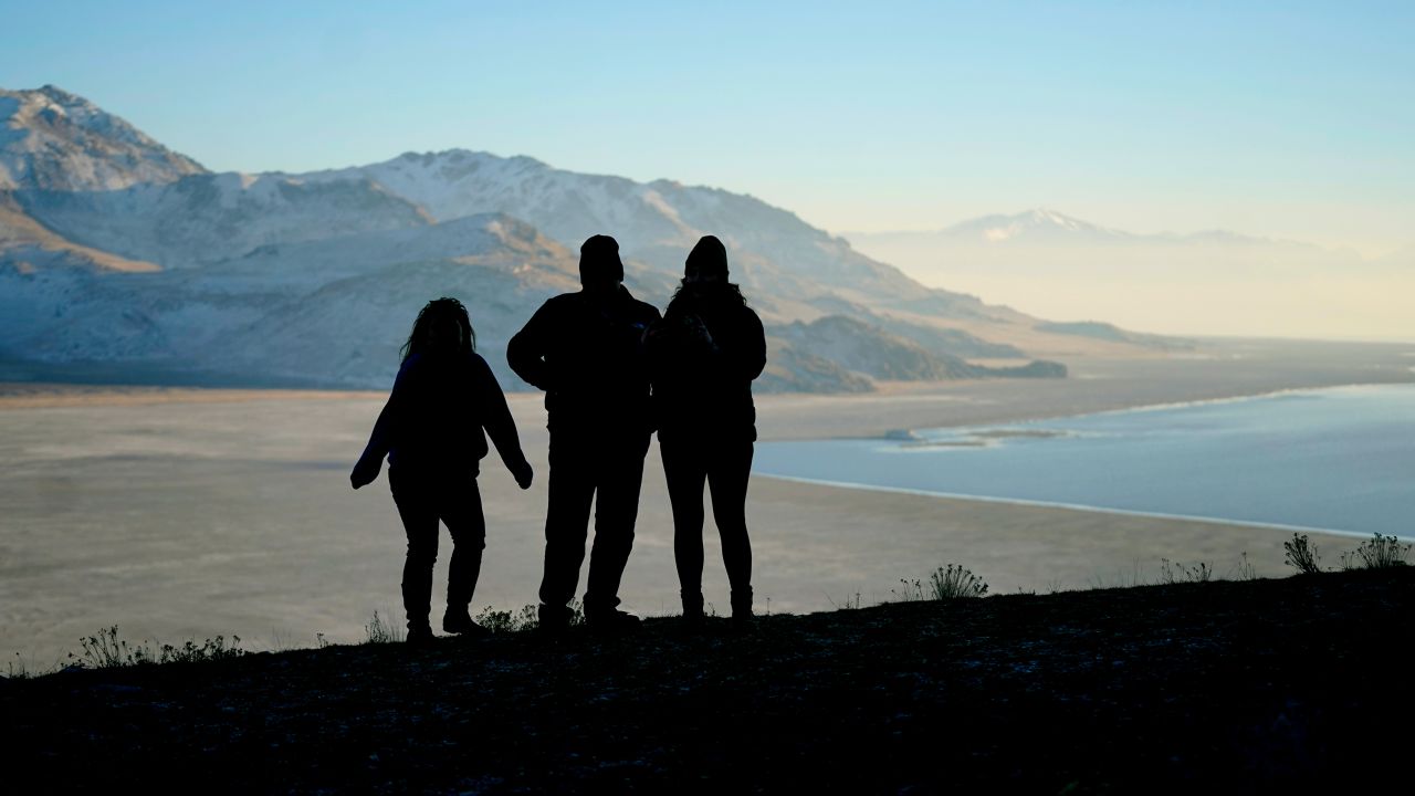Visitors to Antelope Island State Park look over the dry lake bed at the receding edge of the Great Salt Lake.