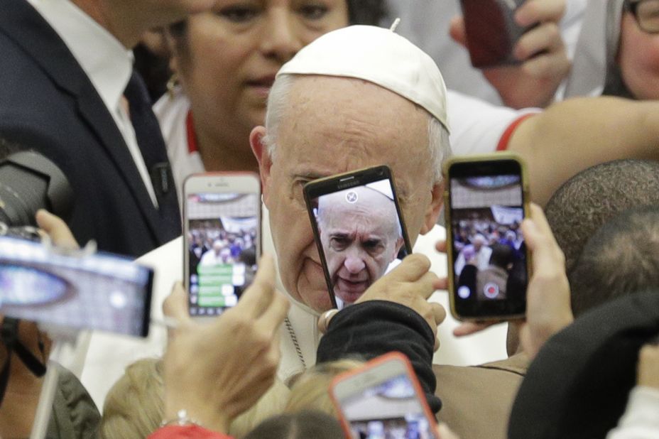Pope Francis is framed by cell phones as he greets people at the Vatican in January 2019.