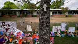 FILE - A cross hangs on a tree at Robb Elementary School on June 3, 2022, in Uvalde, Texas, where a memorial has been created to honor the victims killed in the recent school shooting. Two teachers and 19 students were killed. As public pressure mounts for more information on the deadly Uvalde school shooting, some are concerned that Texas officials will use a legal loophole to block records from being released — even to the victims' families — once the case is closed.